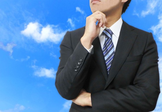 顎に手を当てて考え事をするビジネスマンの写真