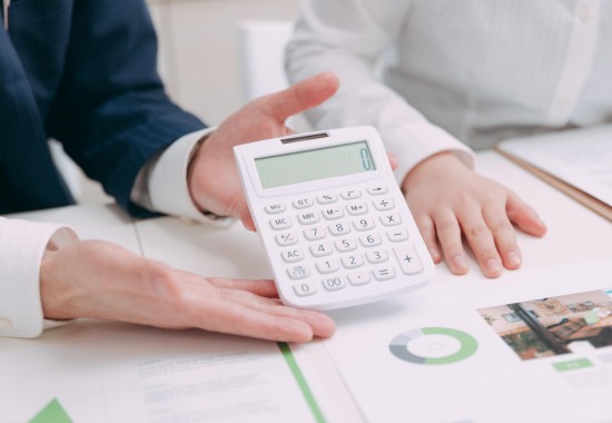 電卓を持った男性の手を撮影した写真